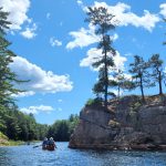 Canoe passing large rock with trees